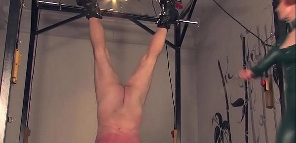  Dominating redhead flogging sub in a bodysuit